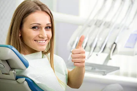 smiling woman in dental chair giving a thumbs up