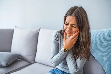 woman holding the side of her face in pain
